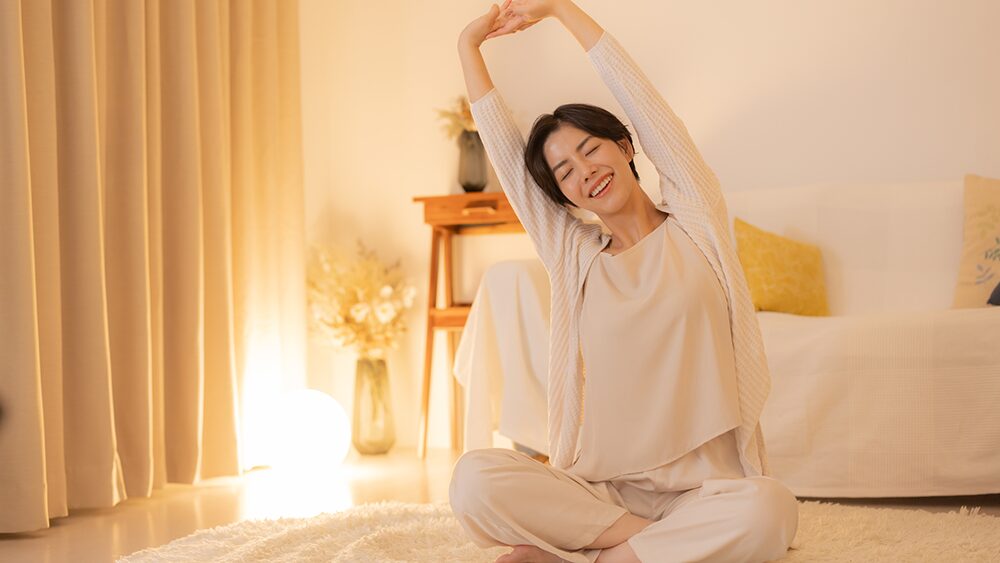 ベッドの上で笑顔で伸びをしている女性