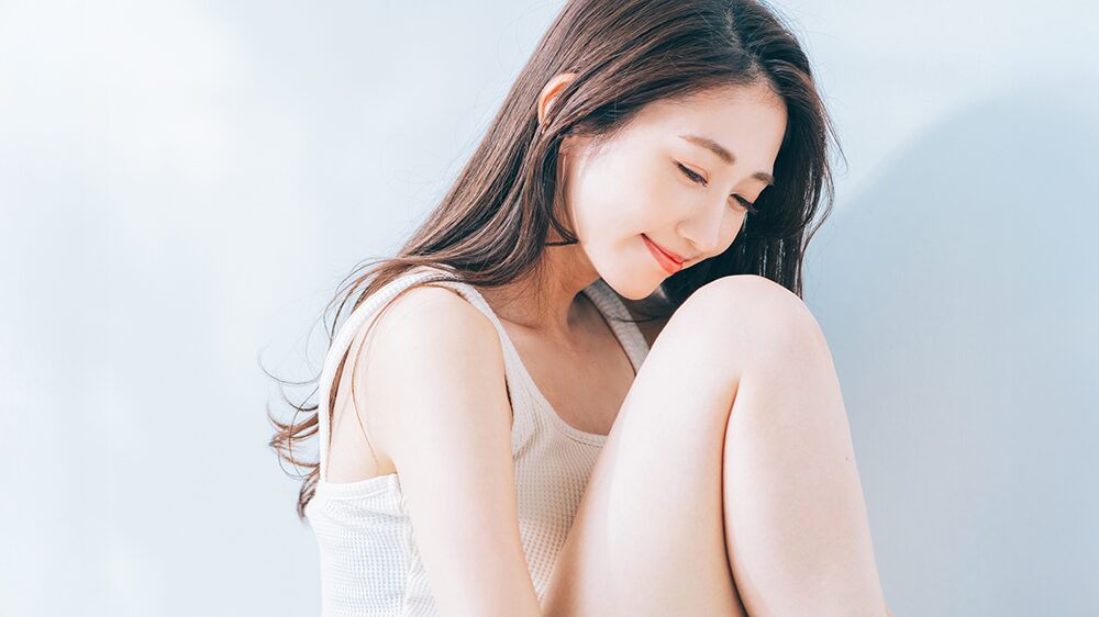 膝を抱えて座る、笑顔の女性の写真