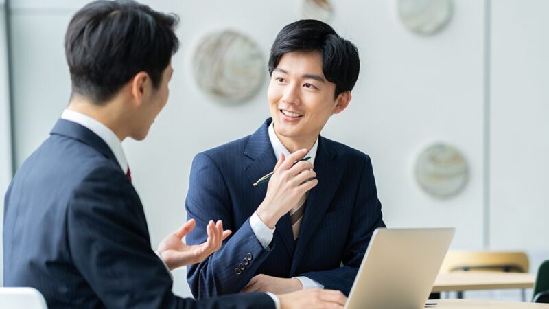 スーツの男性2人が笑顔で話し合っている写真