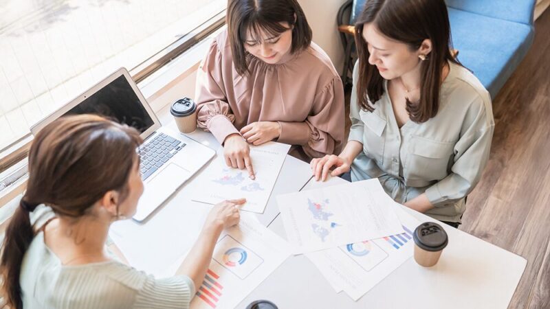 データを見ながら女性社員3人が話し合っている写真