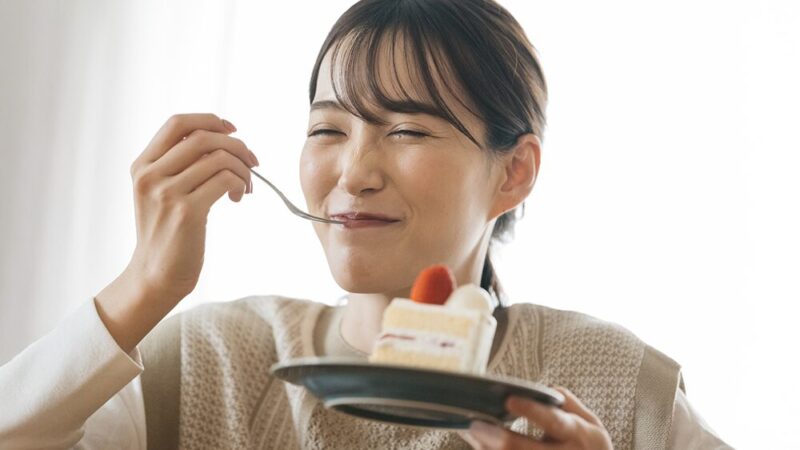 笑顔でケーキを頬張っている女性の写真