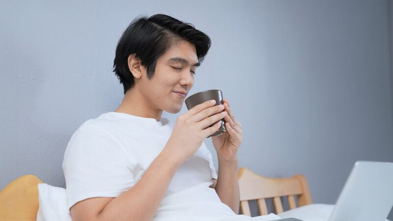 コップを両手で持ち、匂いを嗅いでいる男性の写真