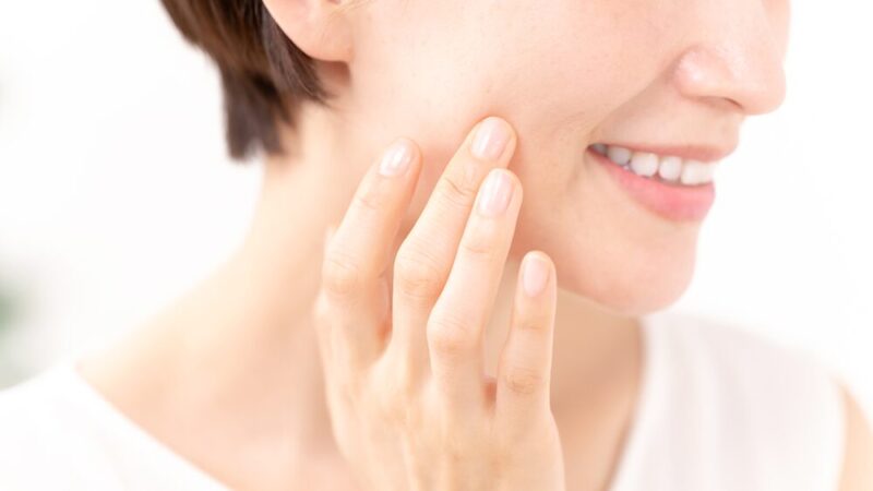 笑顔で頬に触れている中年女性の写真