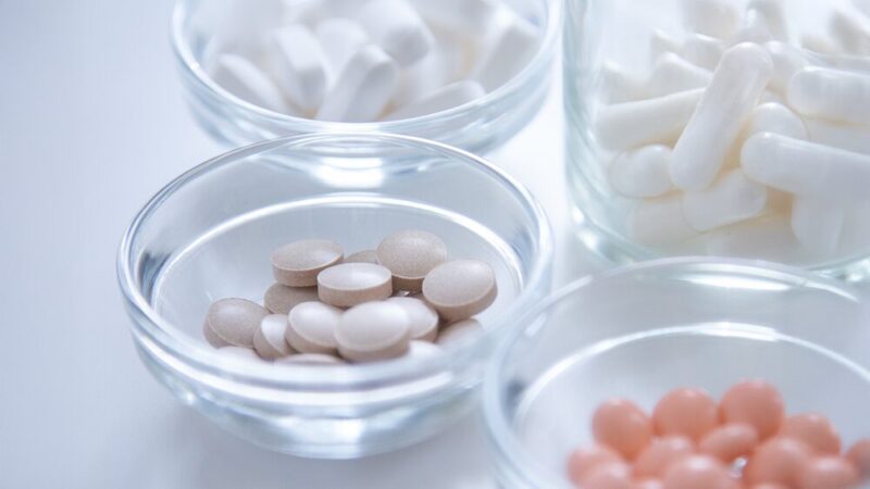 打錠やカプセルなど、グラスに入ったサプリメントの写真