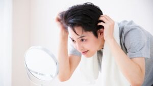 男性が鏡を見て頭髪を気にしている写真