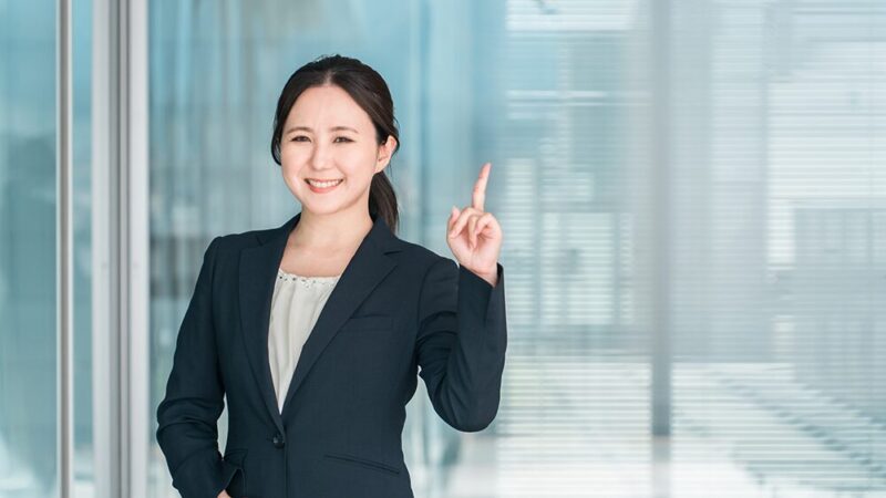 人差し指を指したスーツの女性の写真