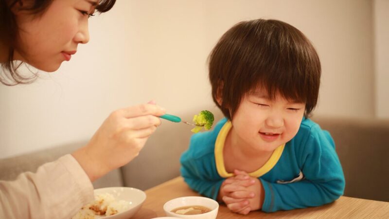 小さな男の子がブロッコリーを食べることを拒否している写真
