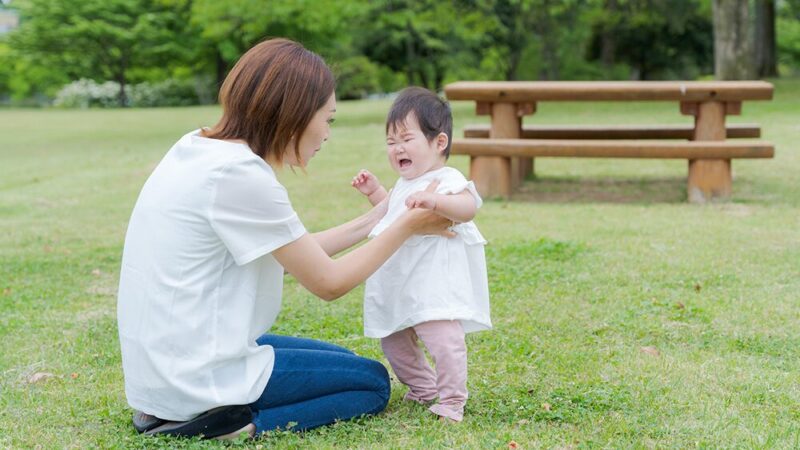 泣いている小さな女の子とその子を抱える母親の写真