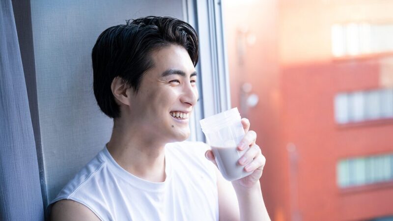 プロテインを笑顔で飲んでいる男性の写真