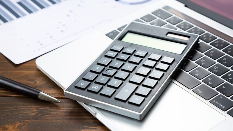 電卓とパソコンと資料の写真