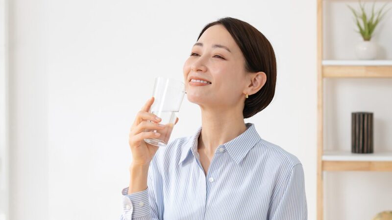 笑顔で飲み物を飲む女性の写真