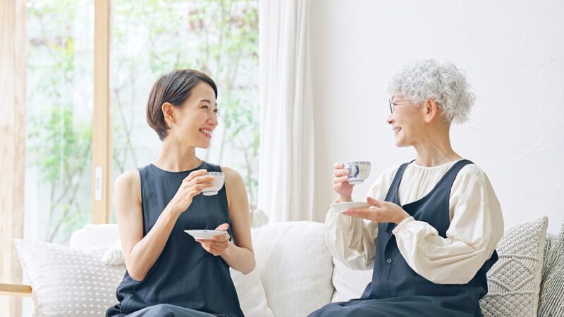 ミドルとシニアの女性が笑顔で優雅にお茶を飲んでいる写真