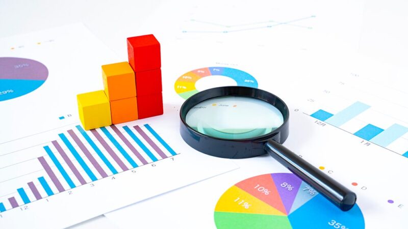 円グラフや棒グラフの資料と虫眼鏡の写真