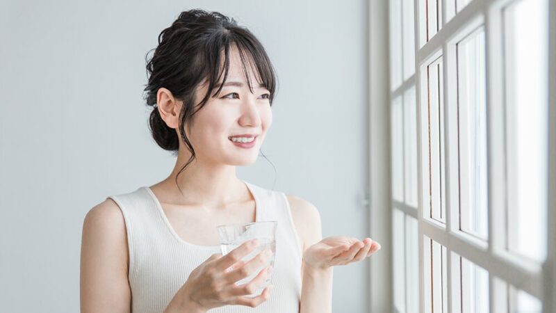 サプリメントと水を持った笑顔の女性の写真