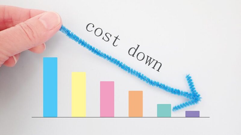 右肩下がりのグラフの上にコストダウンと書いた紙の写真