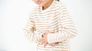 苦悶の表情でおなかにt両手を当てる子どもの写真