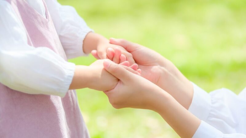 小さな子どもの手を握る女性の手の写真