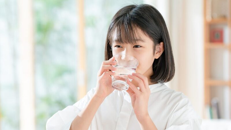笑顔で水を飲む子どもの写真