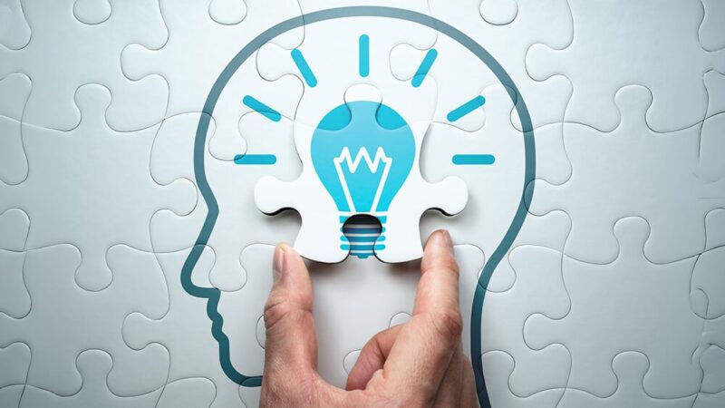 頭の中にある電灯が点灯したジグソーパズルをはめている写真