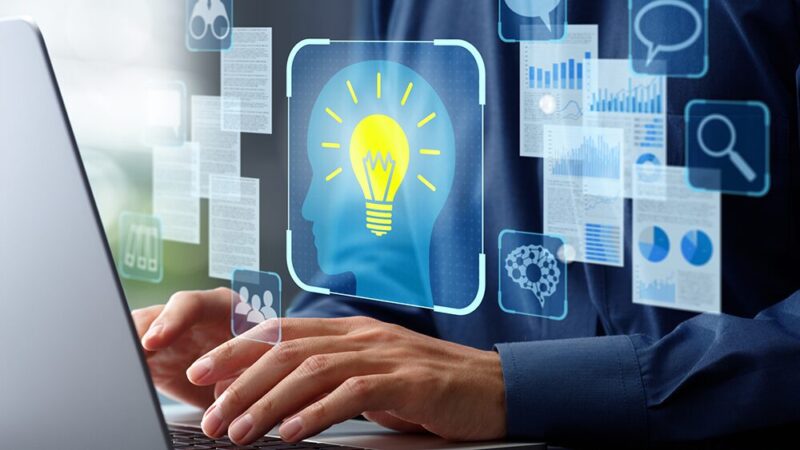 ノートパソコンでタイピングする男性の前に、複数のデータとひらめいたイラストが浮かび上がった写真