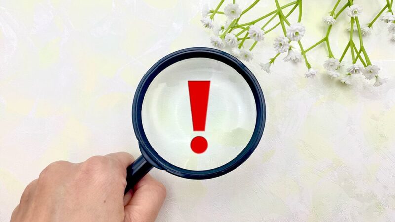 虫眼鏡で「!マーク」を覗き込んでいる写真