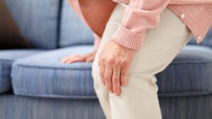 ソファに片手をつき、曲がった膝に手を当てている写真